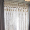 Rideau Macramé Brie Atelier Macramé devant une fenêtre et un mur gris